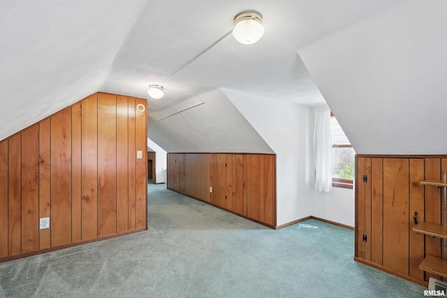 additional living space with wooden walls, baseboards, carpet, and lofted ceiling
