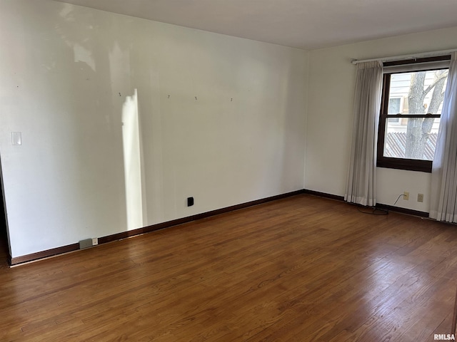 empty room with baseboards and dark wood finished floors