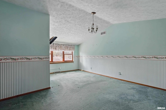 empty room featuring a textured ceiling, a chandelier, carpet, lofted ceiling, and visible vents