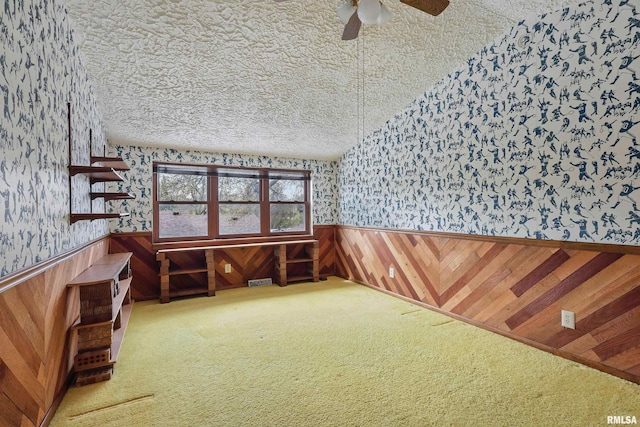 empty room featuring a ceiling fan, wainscoting, wallpapered walls, and carpet flooring
