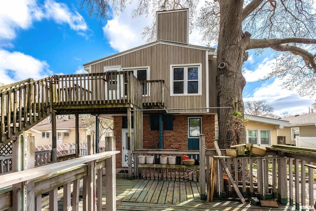 rear view of property featuring brick siding, a chimney, and a deck