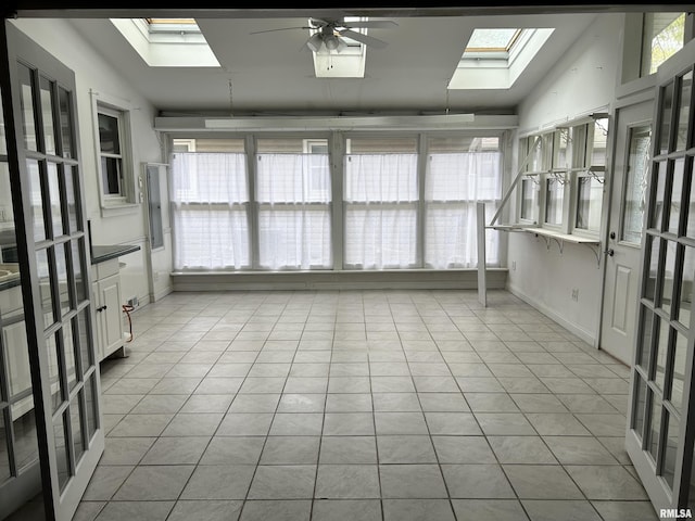 unfurnished sunroom featuring baseboards, lofted ceiling with skylight, and tile patterned floors
