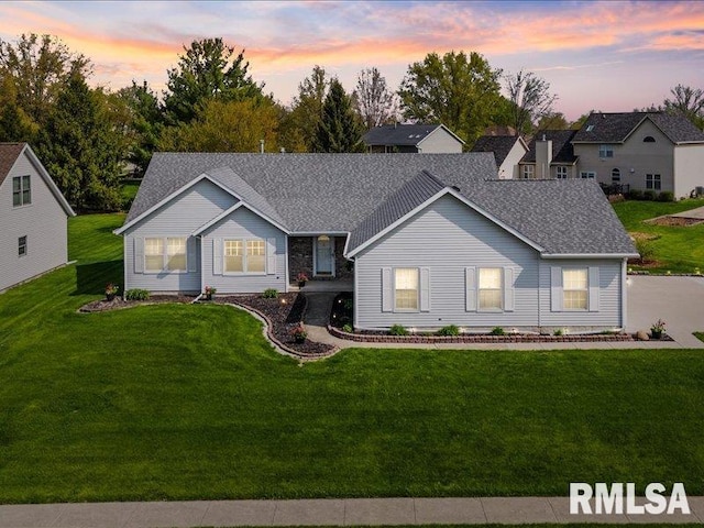 ranch-style house featuring a lawn and a shingled roof
