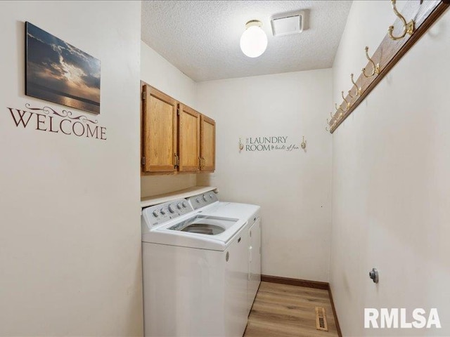 laundry room featuring independent washer and dryer, cabinet space, a textured ceiling, light wood-style flooring, and visible vents