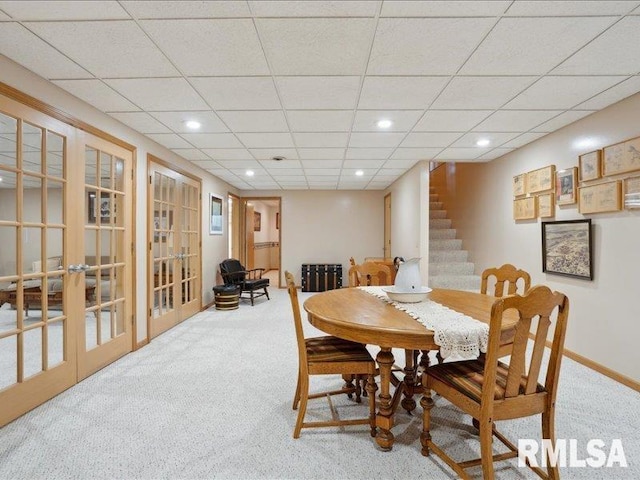 carpeted dining area featuring baseboards, stairway, recessed lighting, a paneled ceiling, and french doors