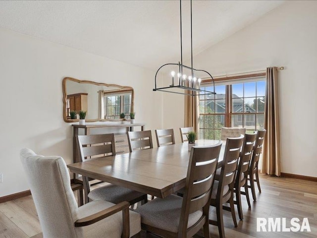 dining room featuring light wood-style flooring, lofted ceiling, a chandelier, and a healthy amount of sunlight