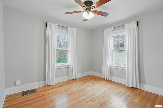 spare room featuring baseboards, a ceiling fan, hardwood / wood-style flooring, and visible vents