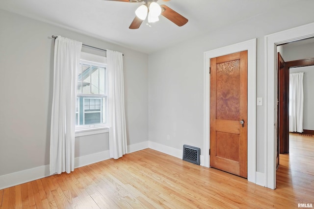 spare room with light wood-style floors, baseboards, ceiling fan, and visible vents
