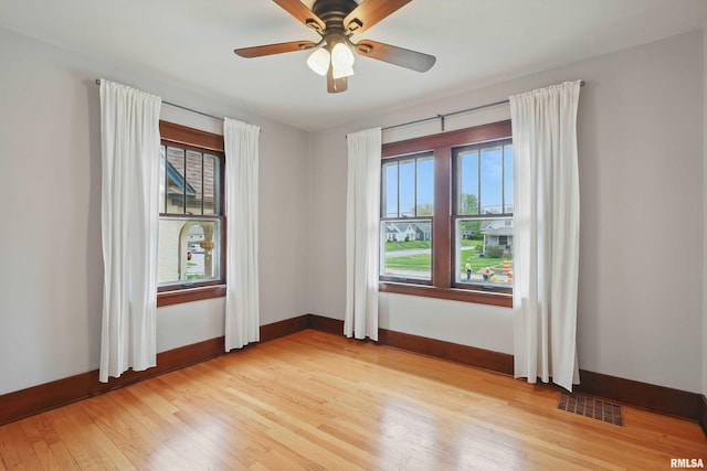 spare room with visible vents, light wood-style flooring, baseboards, and a wealth of natural light