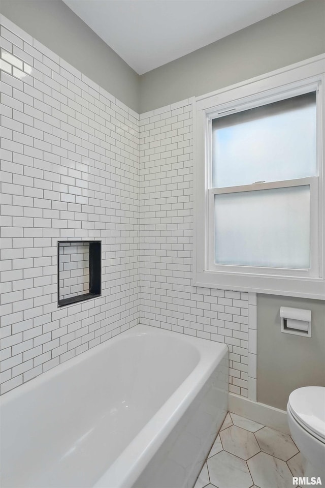 bathroom featuring a washtub, toilet, baseboards, and tile patterned flooring