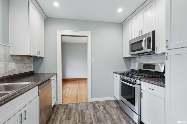 kitchen featuring appliances with stainless steel finishes, white cabinets, dark countertops, and tasteful backsplash