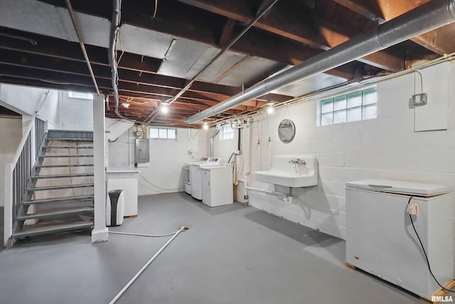 basement featuring independent washer and dryer, a sink, refrigerator, stairway, and electric panel