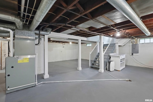 basement featuring heating unit, electric panel, and stairs