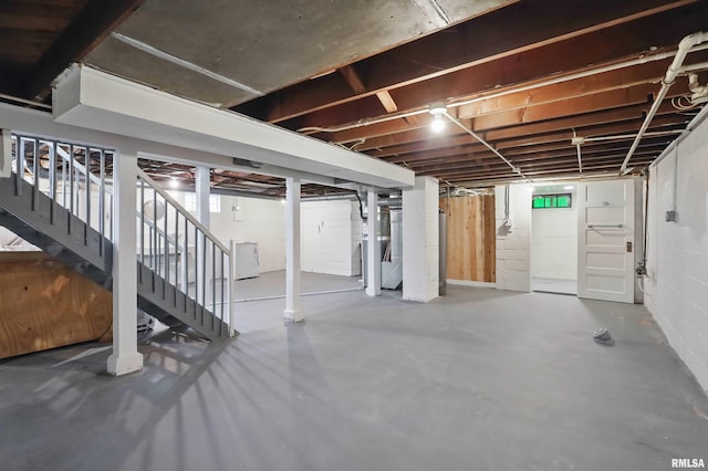unfinished below grade area featuring stairs and washer / clothes dryer