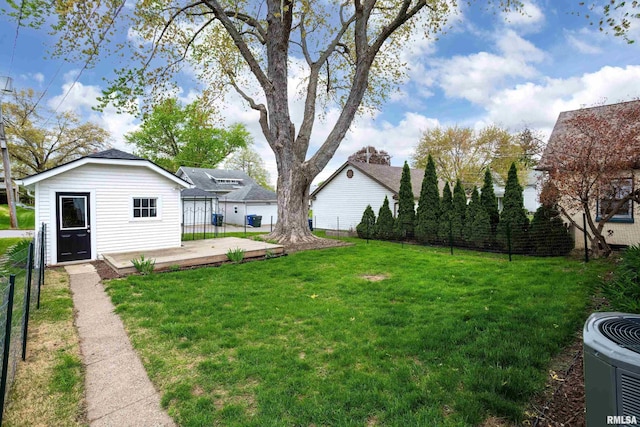 view of yard with fence, a wooden deck, an outbuilding, and cooling unit