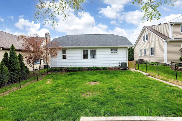 rear view of house with a lawn, central AC, and fence