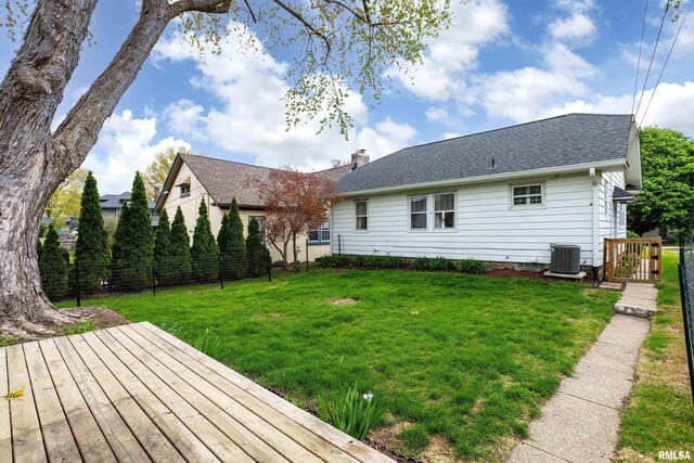 back of property with central AC, fence, a deck, a chimney, and a lawn