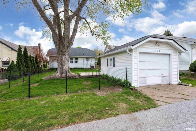 exterior space featuring a lawn, aphalt driveway, fence, and a detached garage