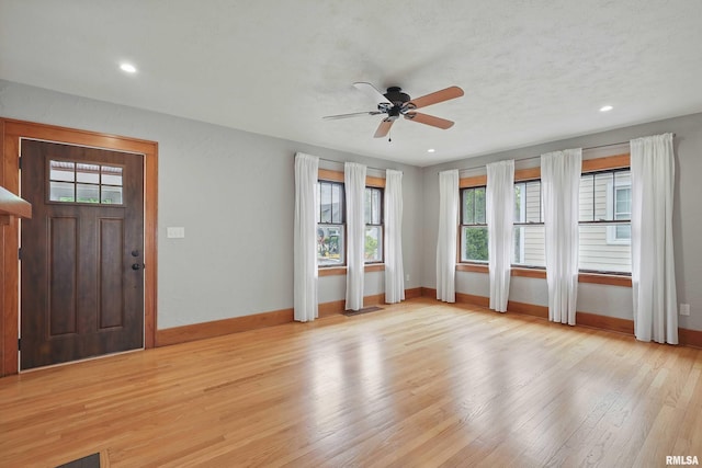 foyer with baseboards, ceiling fan, light wood finished floors, and a wealth of natural light