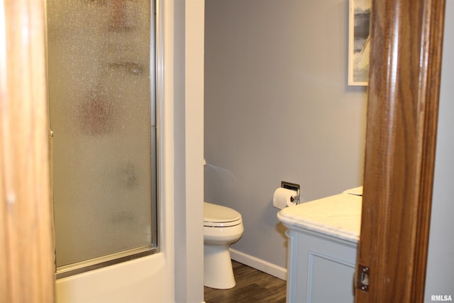 full bath featuring vanity, wood finished floors, toilet, baseboards, and an enclosed shower