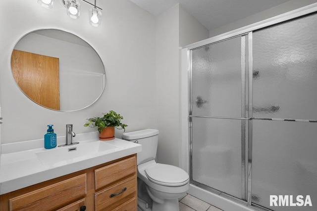 bathroom featuring vanity, toilet, tile patterned flooring, and a stall shower