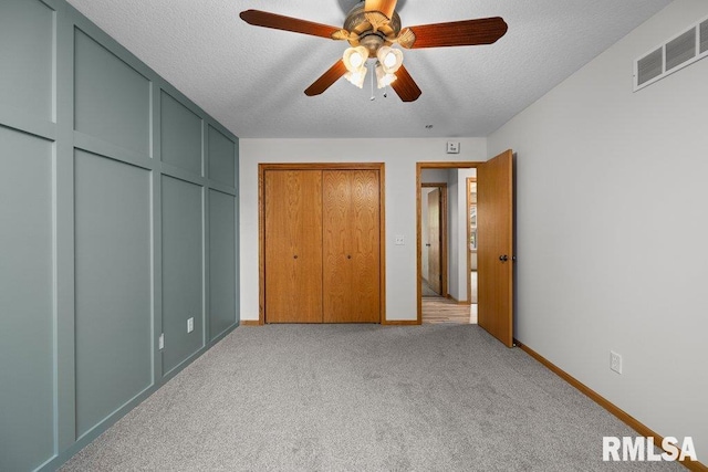 unfurnished bedroom with ceiling fan, light carpet, a textured ceiling, baseboards, and visible vents