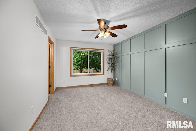 unfurnished bedroom with carpet floors, a textured ceiling, a ceiling fan, baseboards, and visible vents