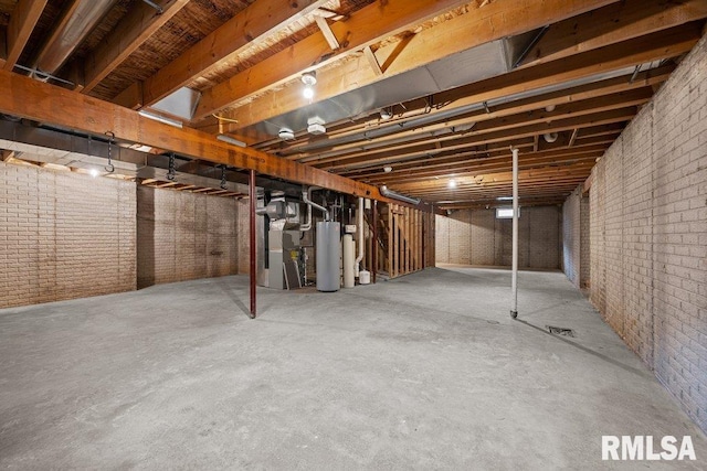 unfinished below grade area featuring heating unit, water heater, and brick wall