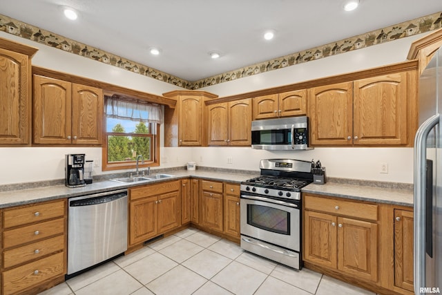 kitchen with recessed lighting, brown cabinets, a sink, appliances with stainless steel finishes, and light tile patterned floors