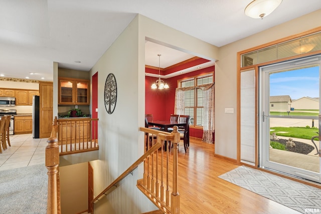 foyer featuring a healthy amount of sunlight, baseboards, an inviting chandelier, and light wood finished floors