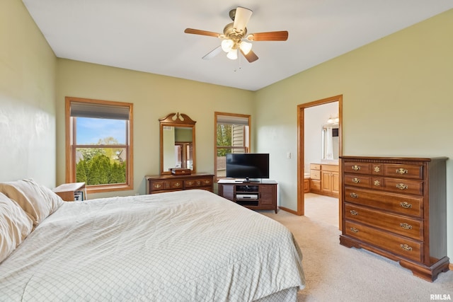 bedroom with light colored carpet, a ceiling fan, connected bathroom, and baseboards