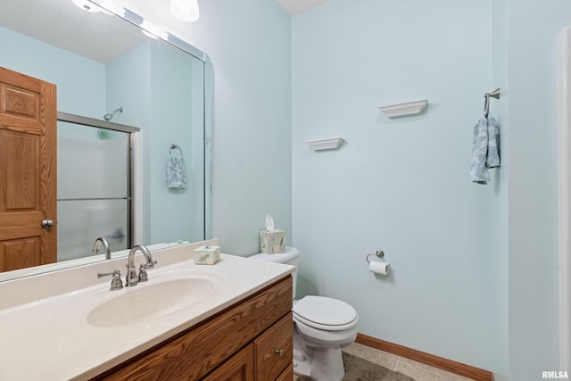 bathroom with toilet, baseboards, a shower with shower door, and vanity