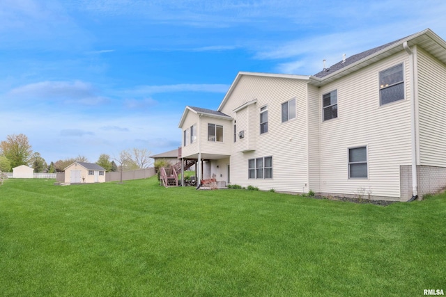 back of property featuring a lawn, fence, and stairway