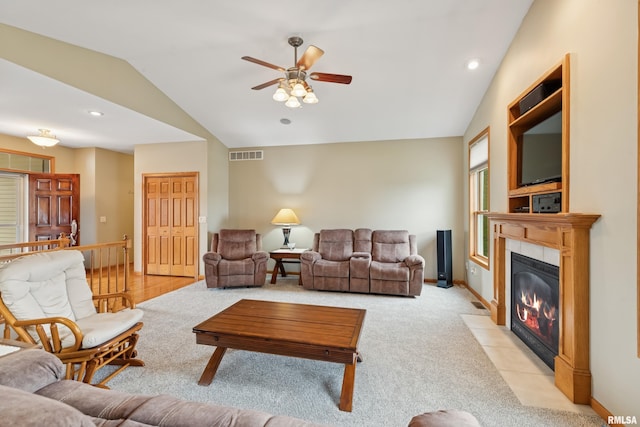 living room featuring visible vents, lofted ceiling, light carpet, ceiling fan, and a tiled fireplace