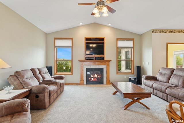living area featuring baseboards, ceiling fan, a tile fireplace, carpet, and vaulted ceiling