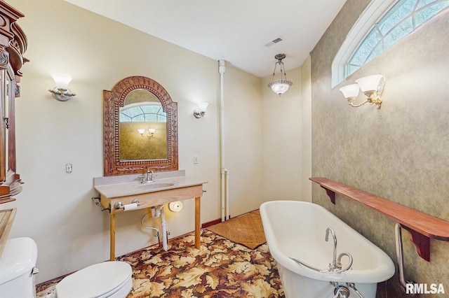 full bath with visible vents, a freestanding bath, a healthy amount of sunlight, and toilet