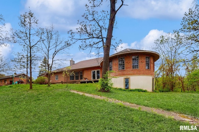 back of property featuring a yard, brick siding, and a chimney
