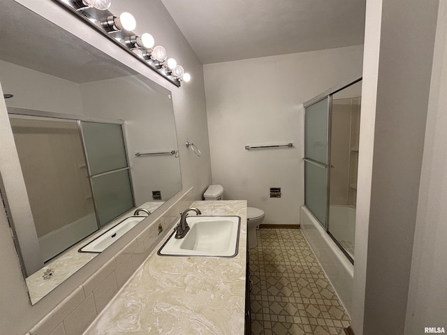 bathroom with vanity, tile patterned floors, baseboards, combined bath / shower with glass door, and toilet
