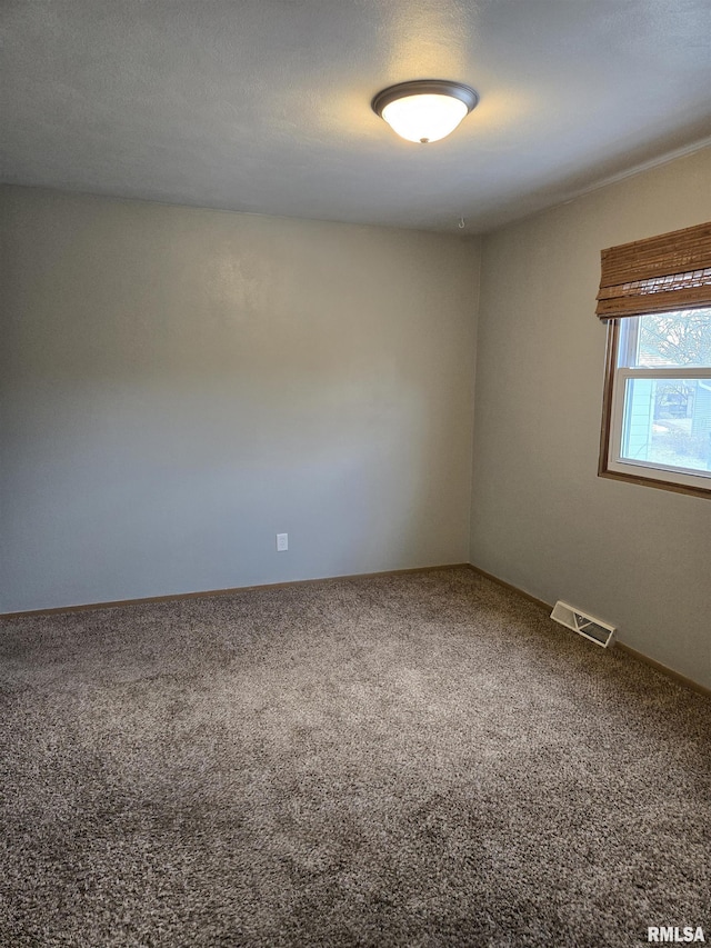 carpeted spare room featuring visible vents