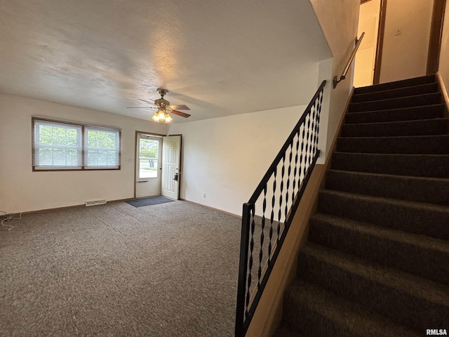 staircase with visible vents, carpet flooring, baseboards, and ceiling fan