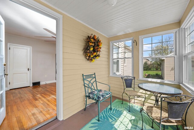 sunroom with visible vents, wood walls, and wood finished floors