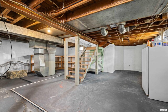 unfinished basement with freestanding refrigerator, heating unit, and stairs