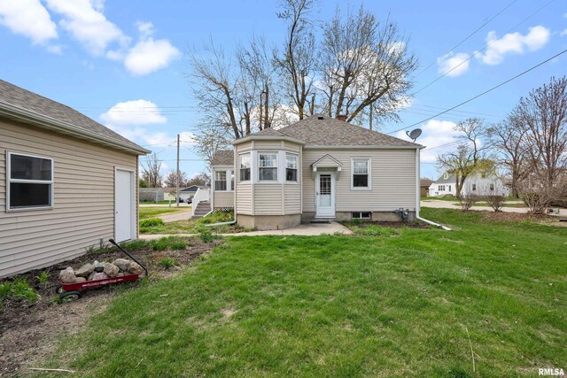 back of property with entry steps, a chimney, and a yard