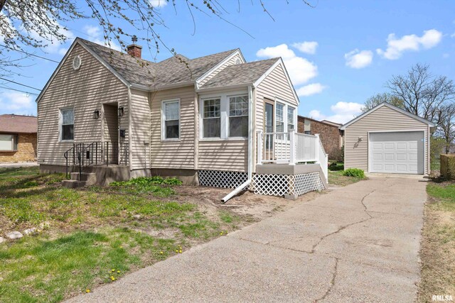 view of front facade with driveway, a chimney, an outbuilding, a garage, and a shingled roof