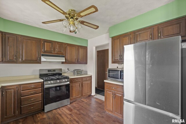 kitchen with ceiling fan, appliances with stainless steel finishes, light countertops, dark wood finished floors, and under cabinet range hood