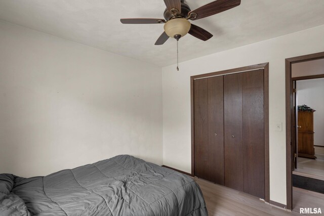 bedroom featuring baseboards, light wood finished floors, ceiling fan, and a closet