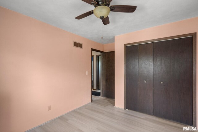 unfurnished bedroom featuring ceiling fan, visible vents, light wood-type flooring, and a closet