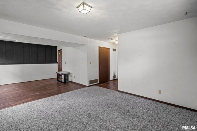 unfurnished room featuring baseboards, dark carpet, and visible vents