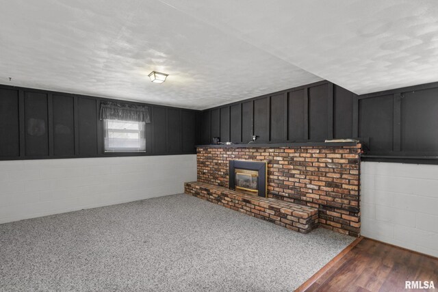 unfurnished living room with concrete block wall, a textured ceiling, and a fireplace