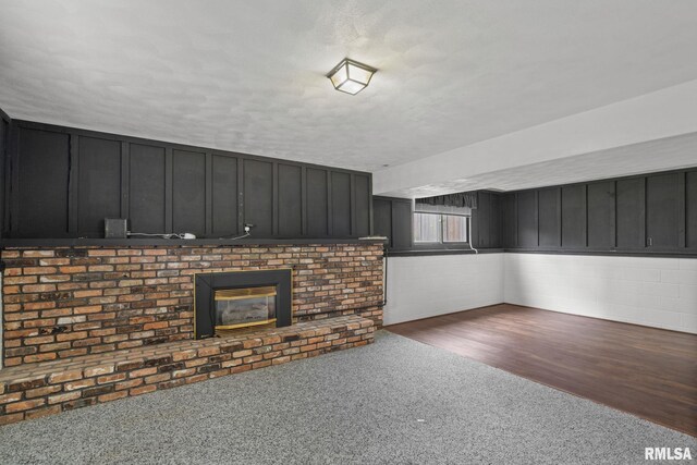 basement featuring carpet, a brick fireplace, and a textured ceiling